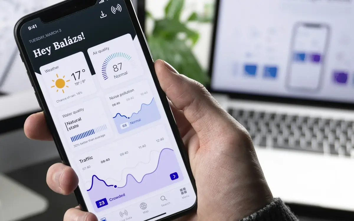 Hand holding a smartphone displaying a modern mobile app dashboard
